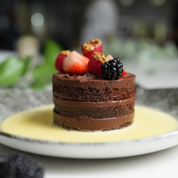 Il Forno a Legna's chocolate cake with berries and a creamy sauce on a plate.