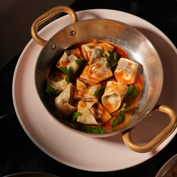 Italian ravioli in a copper pan with red sauce, black pepper, and parsley.