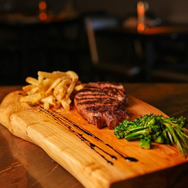 Grilled steak with french fries and broccoli on a wooden board at Il Forno a Legna.